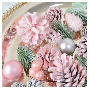 Close-up of pink and silver pine cones with festive pearls and needles on a tray