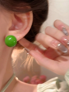 Detail view of vibrant green round stud earring with S925 silver needle on ear
