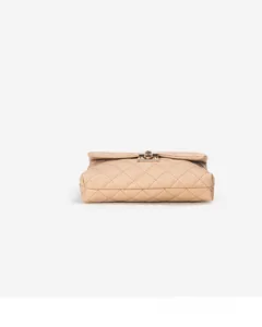 Detail view of beige quilted handbag with gold rotating lock and structured bottom side
