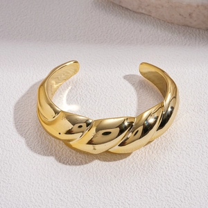 Macro detail of minimalist gold twisted bangle featuring polished spiral texture and a C-shaped cuff