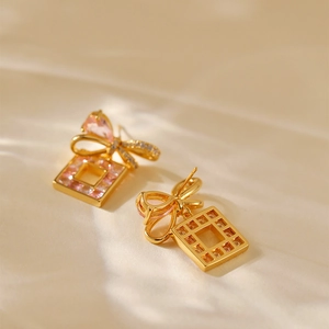 Elegant 18K gold-plated bow earrings with pink square zircon stones on soft fabric