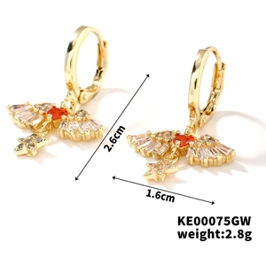 Detailed view of gold earrings with cubic zirconia and red stones in wing design
