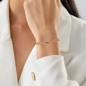 Double-layer gold evil eye bracelet for women shown on wrist with elegant white blazer