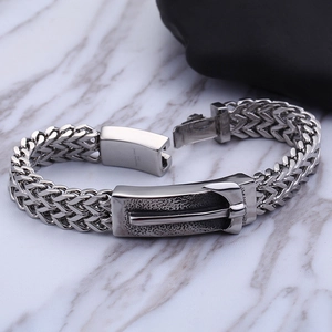 Macro detail of men's stainless steel braided bracelet with buckle on white marble