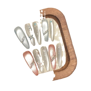 Elegant cat eye press-on nails with butterfly motifs, rhinestones, and pearls on long stiletto tips