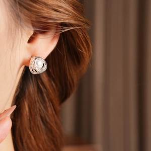 Close-up of a silver spiral pearl stud earring worn on model for a vintage aesthetic