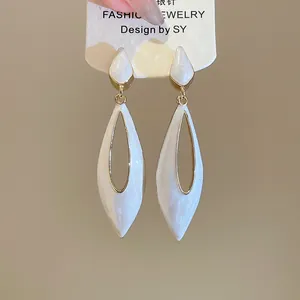 Detailed close-up of 925 silver needle water drop earrings with white enamel and gold finish