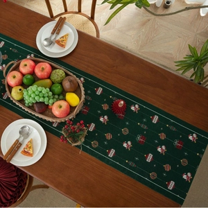 Detailed top view of a dark green Christmas table runner with festive Santa motifs