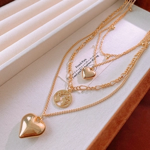 Detailed macro of gold-layered necklace with heart pendants and globe coin in a gift box