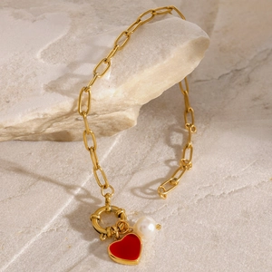 Detail of red enamel heart pendant and pearl on 18k gold-plated stainless steel chain