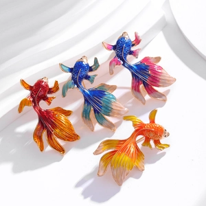Detail of four colorful enamel goldfish brooches with refined gold-plated metal edges