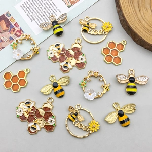 Flat lay of yellow enamel bee and honeycomb alloy pendants with rhinestones for DIY jewelry