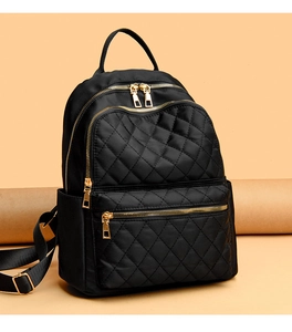 Detail of black quilted backpack with gold zippers and multiple storage compartments