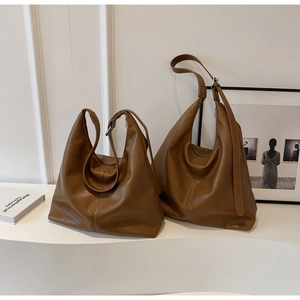 Minimalist pair of brown leather hobo shoulder bags for women in a studio setting