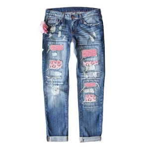 Jeans blu strappati con toppe glitterate rosa e dettagli leopardati su sfondo bianco