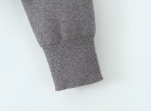 Detail shot of the ribbed cuff craftsmanship and fine knitted texture in dark grey
