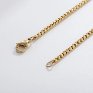 Detailed macro shot of a gold-plated box chain with a sturdy lobster clasp fastening