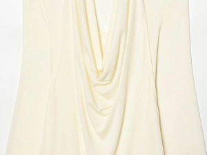 Detailed view of the soft drape neck and creamy white knit fabric texture on this long sleeve top