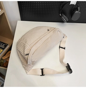 Close-up of beige corduroy waist bag with adjustable strap and dual zipper pockets