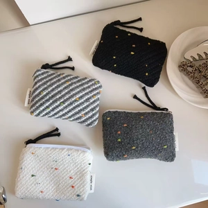 Vista dall'alto di portamonete in tweed a pois colorati con etichetta e zip a corda