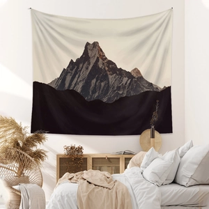 Bohemian tapestry featuring sunset mountain peak scenery hanging in a minimalist bedroom