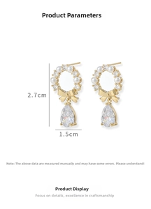 Detail of gold bow earrings with pearl circles and teardrop zircon pendant