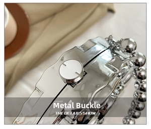 Detail of silver mirror evening bag featuring a metal clasp and beaded pearl handle