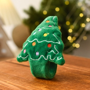 Close-up of plush green Christmas tree snap bracelet with colorful embroidery on wood