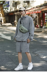Male model in grey street style suit wearing a light green leisure crossbody chest bag