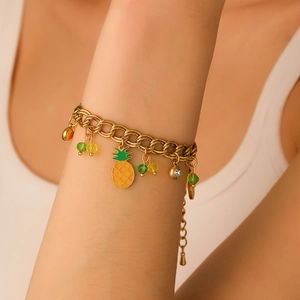 Close-up of golden pineapple charm bracelet with colorful beads on model wrist
