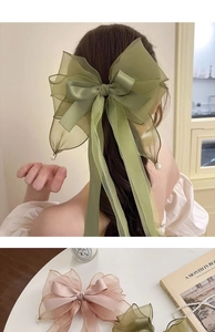 Detail of oversized fabric bow hair clip with pearl pendant and multi-layer organza ribbon