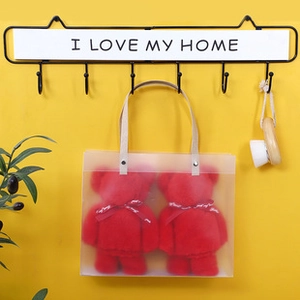 Detail of bear towels in clear gift bags with a 6-hook wall rack on a yellow background