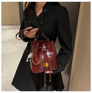 Détail du sac seau bordeaux brillant avec une élégante breloque boule de billard numéro 8