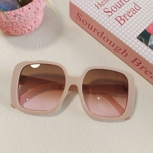Close-up of nude pink heart sunglasses with gradient lenses on a styled tabletop