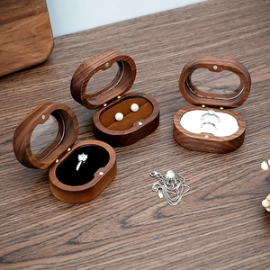 Macro shot of oval walnut wood jewelry boxes with black, brown, and white velvet inserts