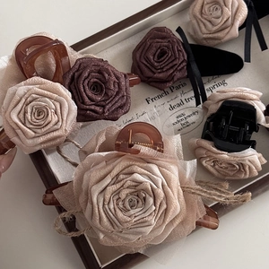 Detailed set of vintage silk rose hair claws in brown and beige tones on wooden tray