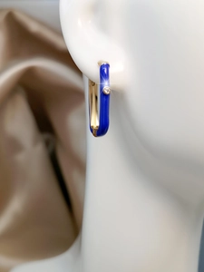 Macro detail of royal blue enamel hoop earring with sparkling zircon and gold trim