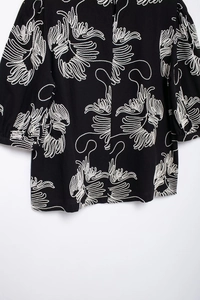 Close-up of intricate white embroidery on a black short-sleeved cotton linen shirt