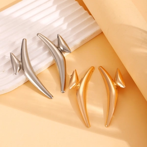 Dettaglio di orecchini irregolari in oro e argento con texture lava su vassoio