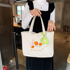 Close-up of quilted off-white canvas tote bag featuring rabbit and tulip embroidery details