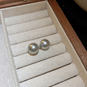 Vue détaillée de boucles d'oreilles perles gris argenté dans un écrin en velours beige