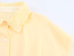 Détail de la broderie en dentelle délicate sur le col et les boutons de la robe chemise jaune