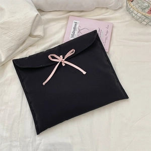Dettaglio di una custodia per laptop nera trapuntata con un delicato fiocco rosa