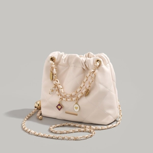 Cream quilted chain bucket bag with heart pendant and luxury gold-tone hardware