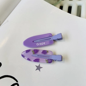 Détail de pinces à cheveux violettes Y2K avec texte Grape et motif raisin scintillant
