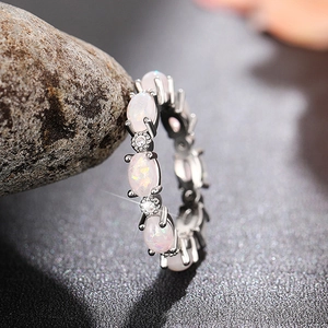 Vue macro d'opale blanche ovale et strass sur une bague d'éternité en argent