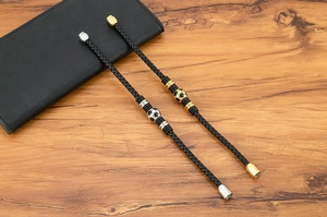 Detail of woven leather football bracelets with silver and gold charms on wood