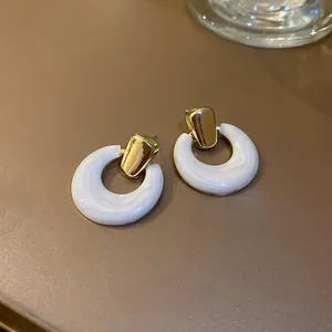 Detailed close-up of cream resin hoop earrings with textured finish and gold metal studs