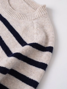 Detail of crewneck collar and soft wool texture on striped knit sweater in beige