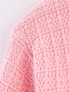 Close-up of pink coarse knit cardigan showing detailed texture on shoulder and sleeve